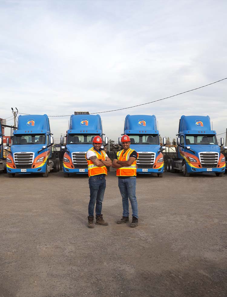 Two Amar Group drivers standing in front of parked Amar trucking equipment
