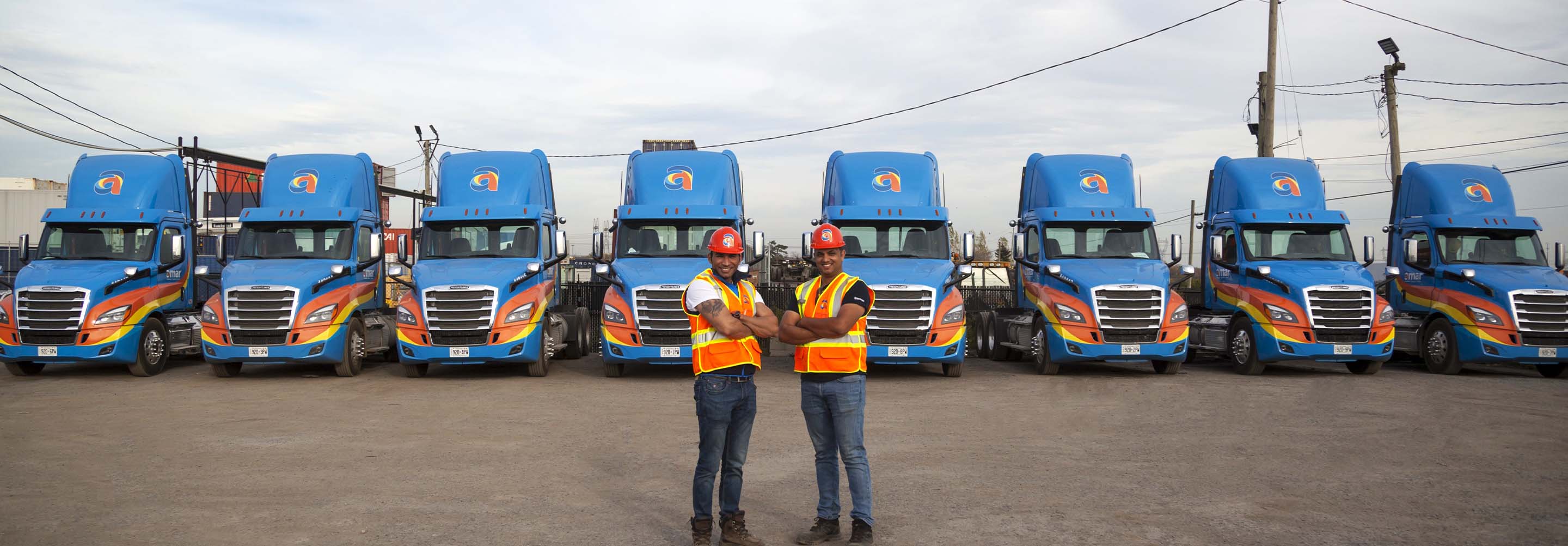 Two Amar Group drivers standing in front of parked Amar trucking equipment