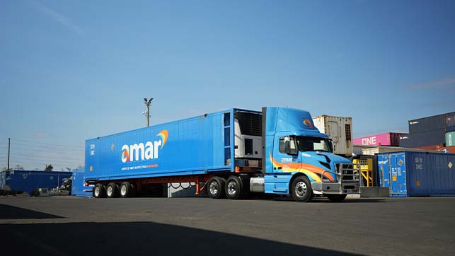 Side view of Amar truck hauling company-owned container