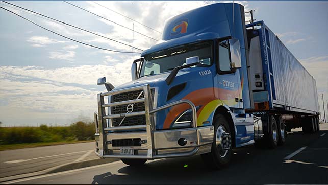 Front view of Amar truck hauling company-owned container on North American highway