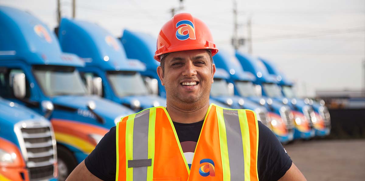 Amar driver smiling in front of Amar trucks parked in the background