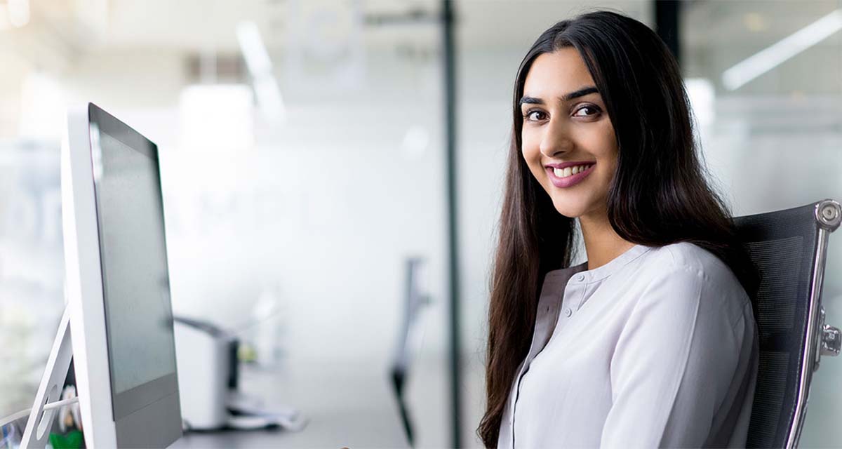 Amar office employee seated at computer smiling