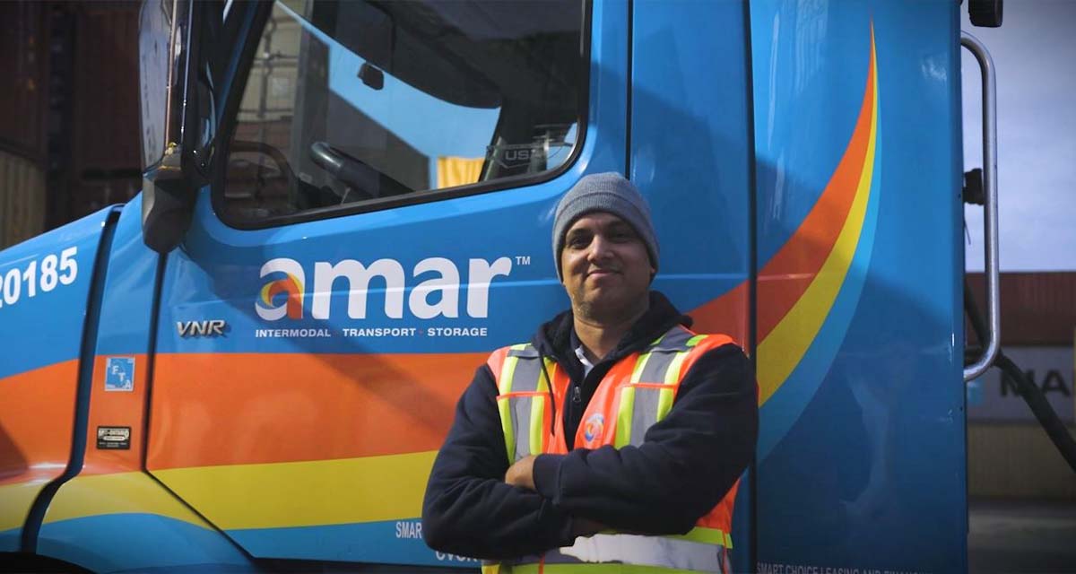 Amar driver standing beside Amar trucking cab
