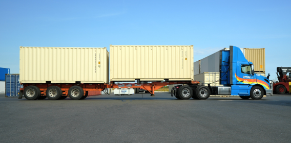 Side view of two specialized freight containers being transported on Amar B-train