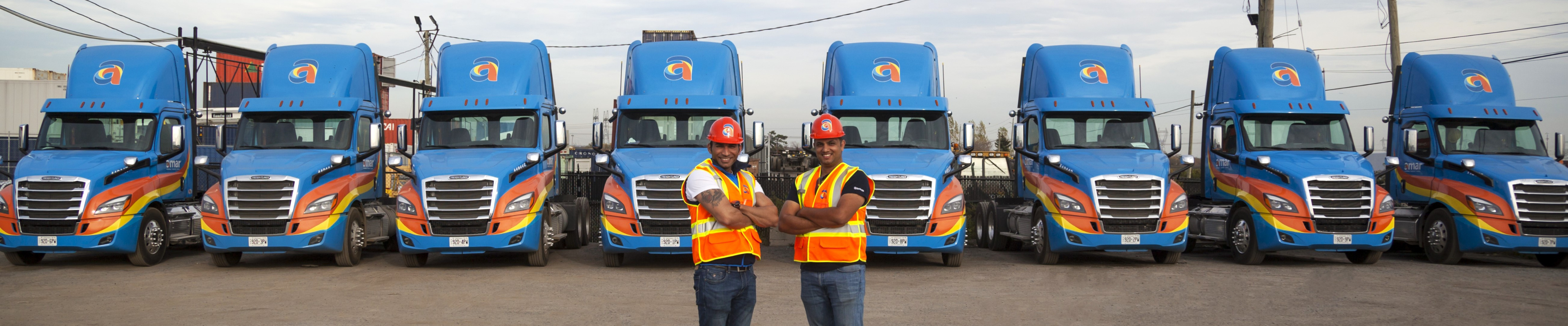 Two Amar Group drivers standing in front of parked Amar Group trucks