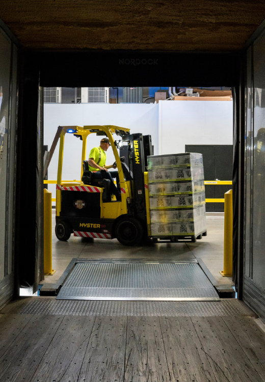 Warehousing employee moving freight pallets utilizing forklift
