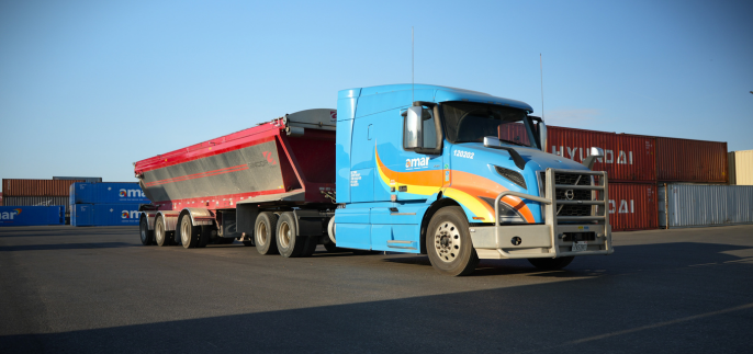 Front view of Amar truck hauling live bottom trailer in container yard