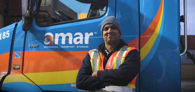 Amar driver standing beside Amar trucking cab